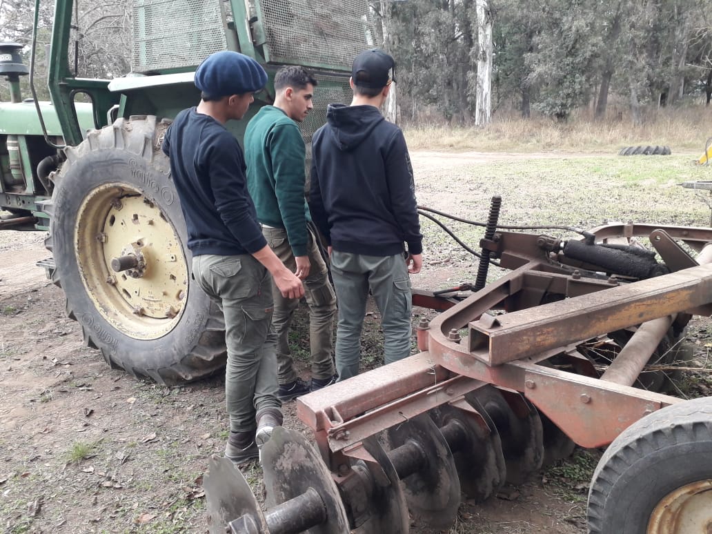 Estudiantes observan una rastra de discos de doble acción enganchada a un tractor